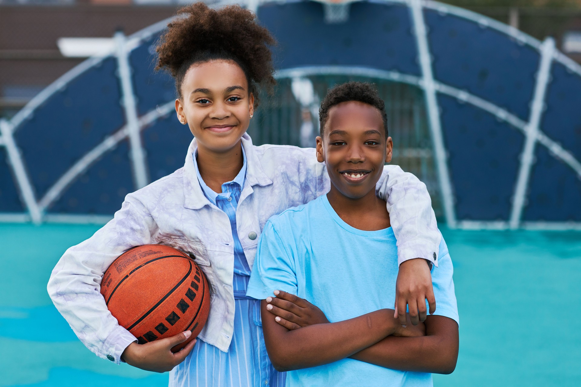 Happy adolescent girl with ball embracing her friend or classmate